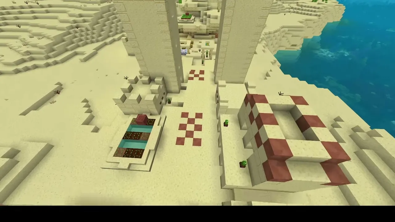 River Border Desert Settlement: closer view of two tall sandstone village towers and houses near the water