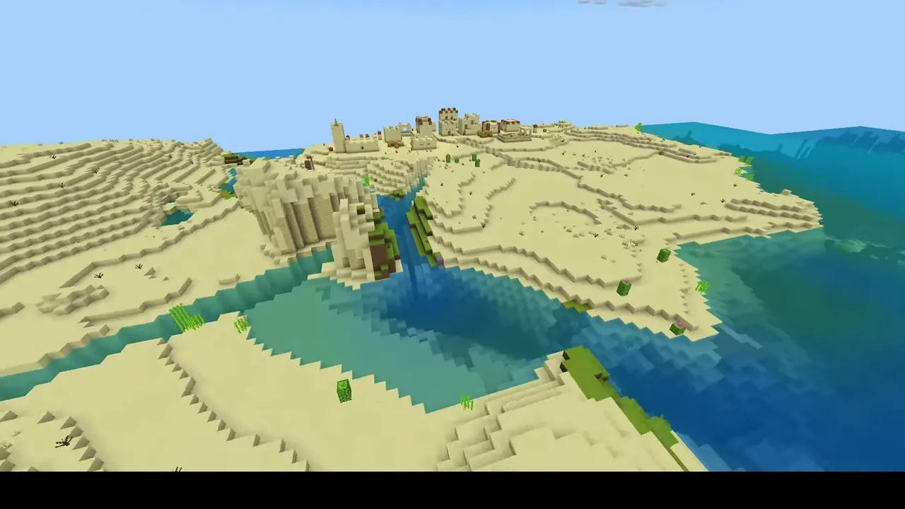 River Border Desert Settlement: wide aerial view of a desert village split by a river channel near the coast